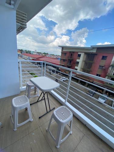 ein Balkon mit einem Tisch und zwei Hockern auf einem Gebäude in der Unterkunft Condominium Primavera Uptown in Cagayan de Oro