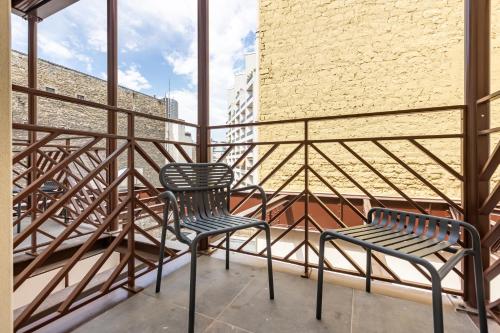 - deux chaises sur un balcon avec un mur en briques dans l'établissement Suites FL By Sweett, à Paris