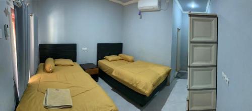 a bedroom with two beds and a book shelf at DEWI HOTEL in Kuta Lombok