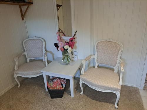two chairs and a table with a vase of flowers at Myntloftet Borlänge med inglasad bubbelbad in Borlänge