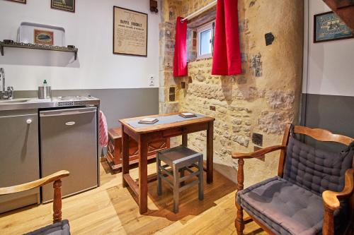 a kitchen with a table and a chair and a sink at La Plus Petite Maison De France in Bayeux