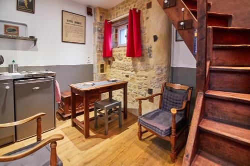 eine Küche mit einem Tisch und eine Treppe in einem Zimmer in der Unterkunft La Plus Petite Maison De France in Bayeux