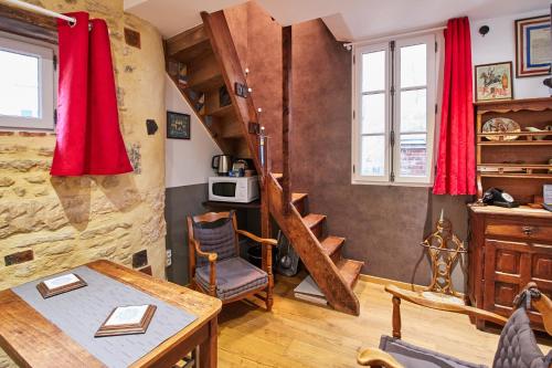 a living room with a wooden table and a staircase at La Plus Petite Maison De France in Bayeux