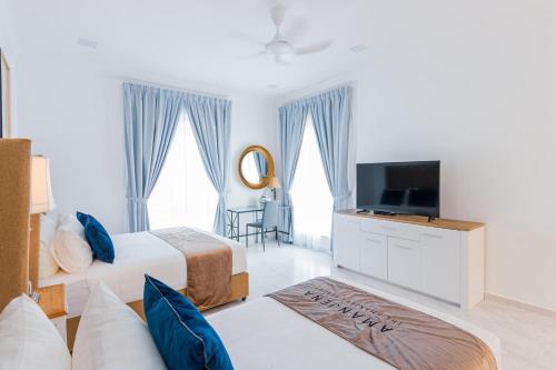 a hotel room with two beds and a television at The Arjana Resort in Masjid Tanah