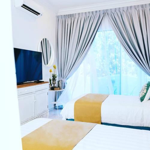 a bedroom with two beds and a tv and a window at The Arjana Resort in Masjid Tanah