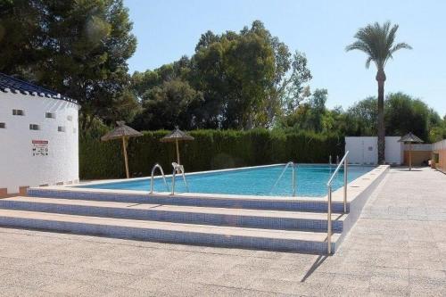 a swimming pool with stairs leading to a pool with a palm tree at Wohnung in Cartagena mit Gemeinschafts Pool und Terrasse in Los Urrutias