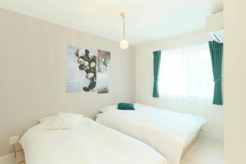 two beds in a room with white sheets at Gran Grace by Tranova in Tokyo