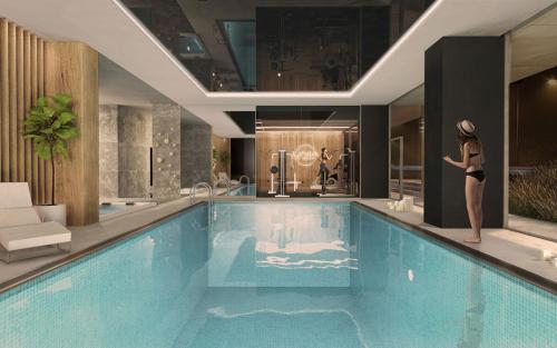 a woman is standing next to a swimming pool at APARTAMENTY ARTE LUBLIN Studio Unia Art Residence 39 - faktura VAT in Lublin