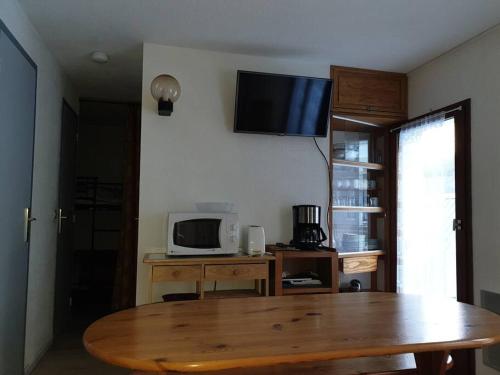 un salon avec une table et une télévision au mur dans l'établissement Appartement au centre de Barèges, à Barèges