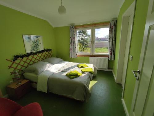 a green bedroom with a bed and a window at Weit draußen und doch mittendrin im Apartment in Thedinghausen