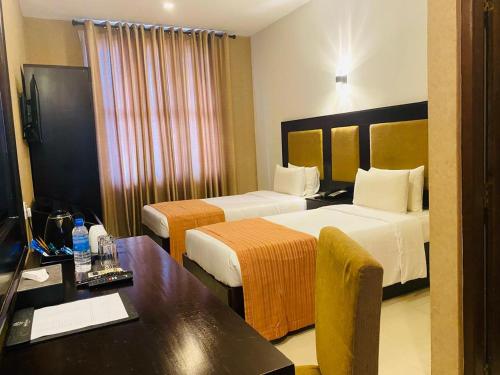a hotel room with two beds and a desk at The Full Moon Hotel Katunayake in Katunayake
