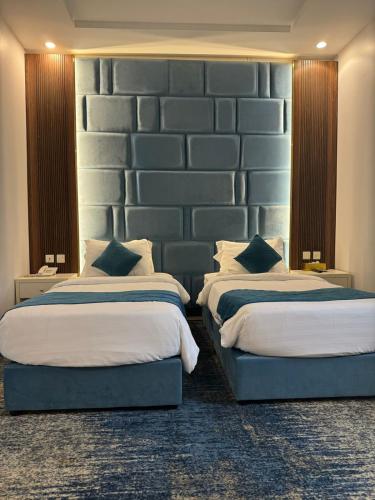 a bedroom with two beds and a large wall at شقق ارين المطار in Jeddah