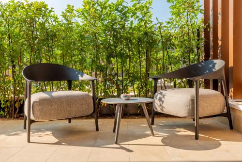 two chairs and a table on a patio with trees at Lifestyle Apartments Dante in Bardolino
