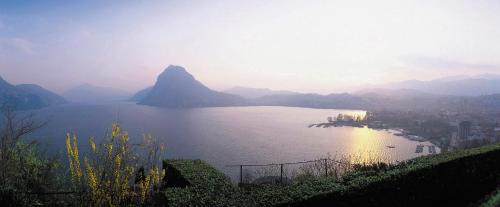 a view of a large body of water with mountains at Hotel Pestalozzi Lugano in Lugano