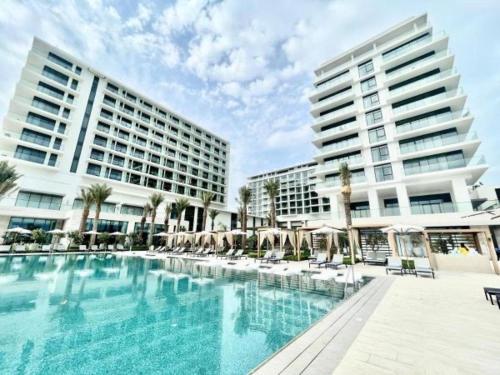 a large swimming pool in front of two tall buildings at Address Beach Resort Residence Bahrain in Rayyā