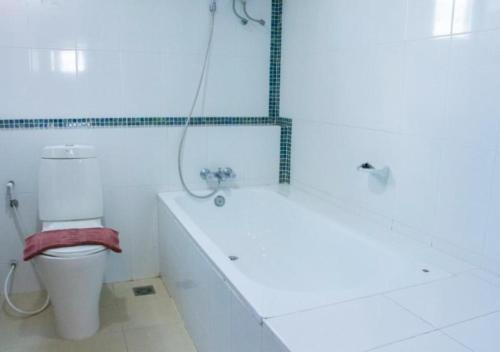 a white bathroom with a tub and a toilet at Convenient Grand Plus Hotel Suvarnabhumi in Lat Krabang