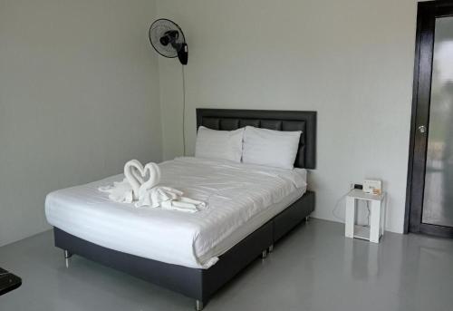 a bedroom with a bed with two white towels on it at Sirimaya Garden Home & Residence in Bang Rak Beach