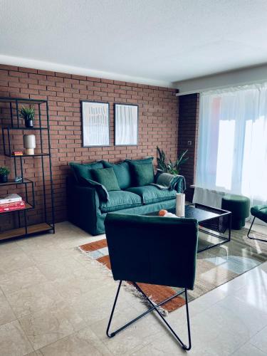 a living room with a green couch and a brick wall at NH 5 Interlaken-Luzern I Lake I Mountain I connect in Sachseln