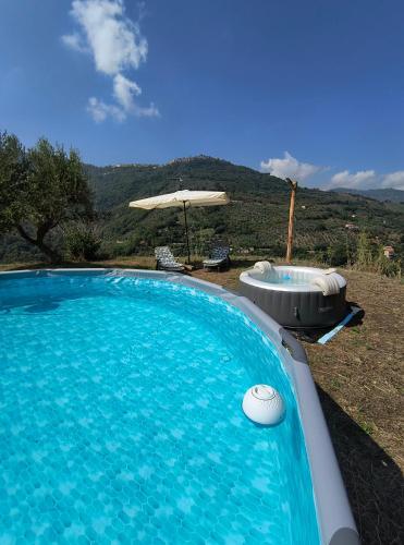 a large swimming pool with a hot tub and an umbrella at L'Antica Quercia B&B in CastellʼUmberto