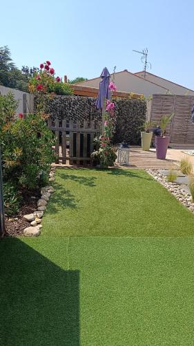 une cour avec de l'herbe verte et un jardin fleuri dans l'établissement Les Mandrines, à Saint-Xandre