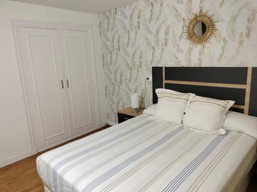 a bedroom with a bed with white sheets and a mirror at Casa Tito 2 in Santo Domingo de la Calzada