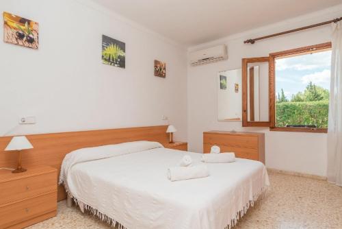 a bedroom with a white bed and a window at Villa Canescandeu in Port de Pollensa