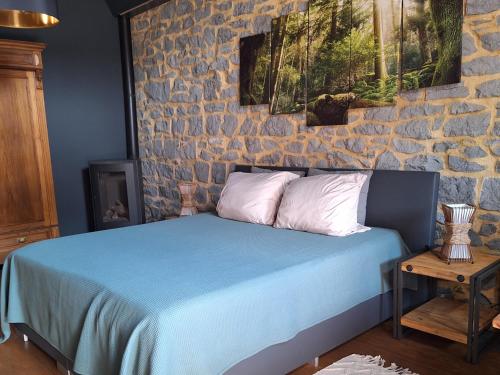 a bedroom with a blue bed with a stone wall at La Laiterie Ecaussinnes in Les Croisettes
