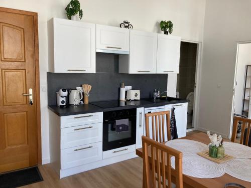 une cuisine avec des placards blancs et une table avec une salle à manger dans l'établissement LocaNice Masséna, à Nice