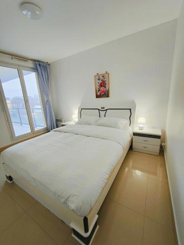 une chambre blanche avec un grand lit et une fenêtre dans l'établissement Appartement 2P à Ivry, aux portes de paris avec parking privé, à Ivry-sur-Seine