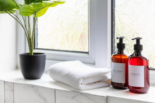a bathroom counter with two bottles of soap and towels at City Gem - 2 Bed House, 6 mins from Liverpool Street, Shops & Restaurants in London