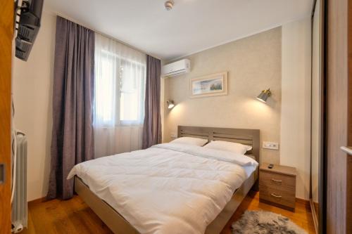 a bedroom with a large white bed with a window at Zlatibor Gold Centar in Zlatibor
