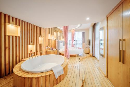 a large bathroom with a tub and a bedroom at Cosy Feeling Hotel - Beijing Headquarters Xinfadi in Beijing