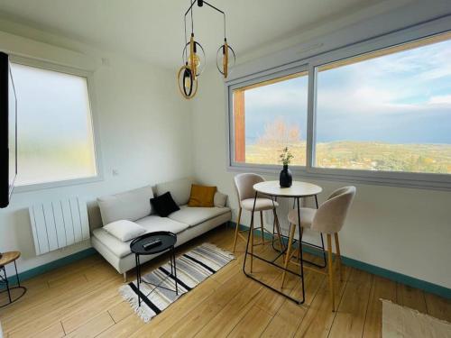 un salon avec un canapé et une table avec des chaises dans l'établissement Studio Ô terrasses de Virieu, à Pélussin