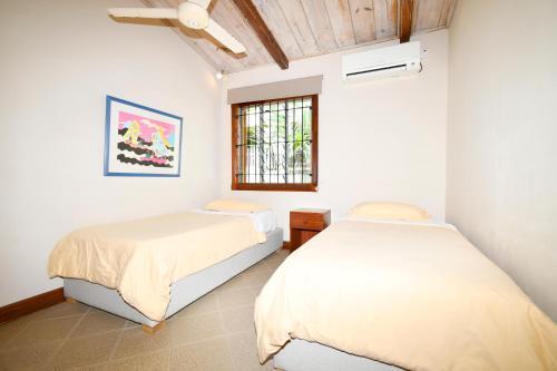 two beds in a room with a window at Villa Alira in Le Morne