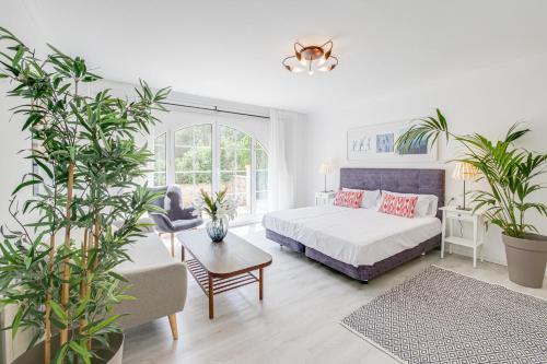 Un dormitorio con una cama y plantas. en G-Fast fertig gestelltes Inserat- Moderne grosse Villa, 5 Min fussläufig zum Strand,Pool,Klima, en Calas de Mallorca