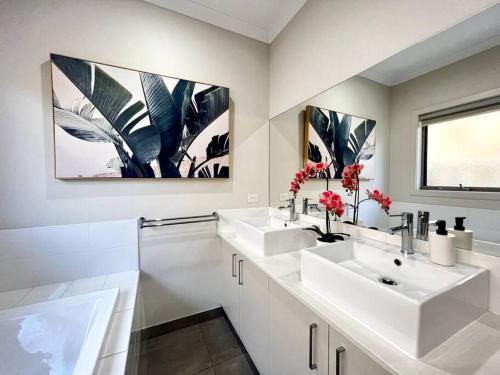 a white bathroom with two sinks and a window at five-room house next to the park16 in Altona Meadows