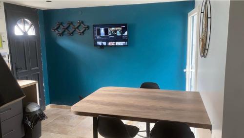 une salle à manger avec une table et un mur bleu dans l'établissement Logement, à Calais
