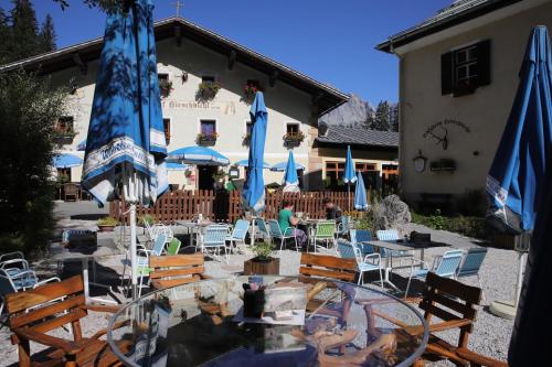 a patio with tables and chairs with blue umbrellas at Appartements Bergheim in Hirschbichl
