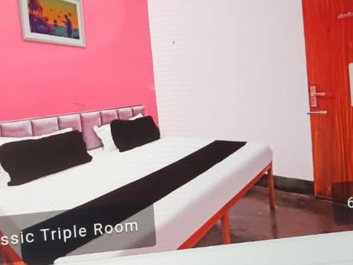 a bed in a room with a pink wall at Flamingo inn-KV tower 2nd floor, Paidleganj Kalepur,Kasia road, Gorakhpur in Gorakhpur
