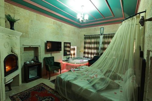 a bedroom with a bed and a living room with a fireplace at Tafana Cave & Stone Lodge in Urgup