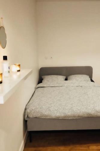 - un lit dans une chambre blanche avec 2 oreillers dans l'établissement Bel appartement proche de Paris - 15 minutes, à Bondy