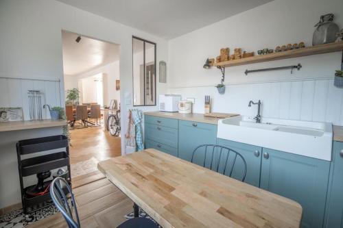 une cuisine avec des placards bleus et une table en bois dans l'établissement Campôse, authentique maison vintage avec spa, 10p, à Gérardmer