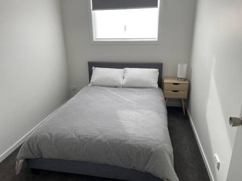 a white bedroom with a bed and a window at New 3 bedroom house in Cooma in Cooma