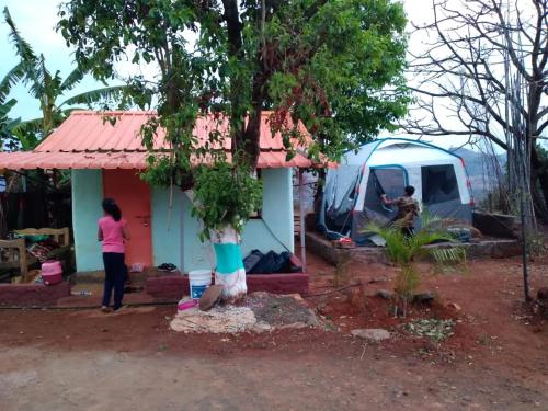 a woman standing next to a small house with a tent at Torna Camp Sites in Welhe