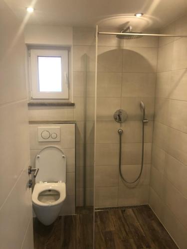 a bathroom with a toilet and a shower with a window at Stilvolle Wohnung im Erdgeschoss in Kolbermoor