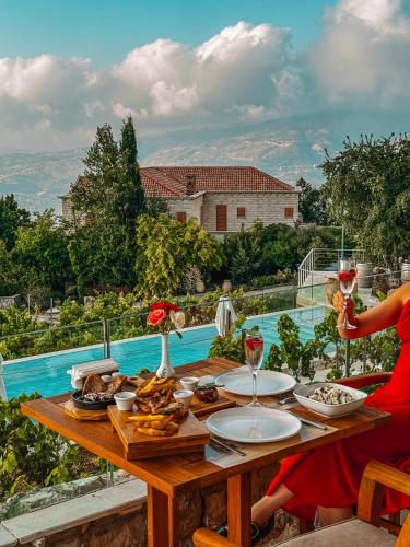 uma mulher sentada à mesa com taças de vinho em KCOR Hotels em Ḩārat at Taḩtā