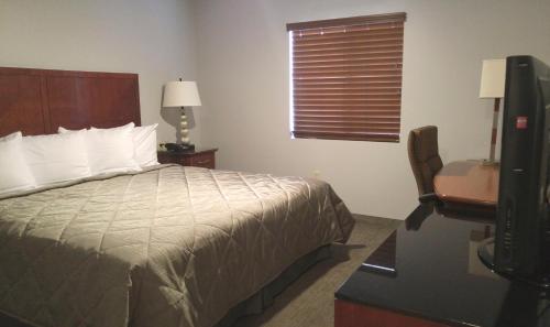 een slaapkamer met een bed, een bureau en een televisie bij Affordable Suites of America Portage in Portage