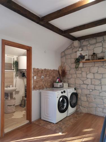 a washing machine in a room with a stone wall at Robinson crusoe style house "MASLINA'' in Škrip