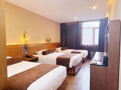 a hotel room with three beds and a television at Cosy Feeling Hotel - Beijing Headquarters Xinfadi in Beijing