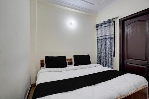 a bedroom with a large bed with black and white sheets at Hotel O Peaceful Paradise in New Delhi
